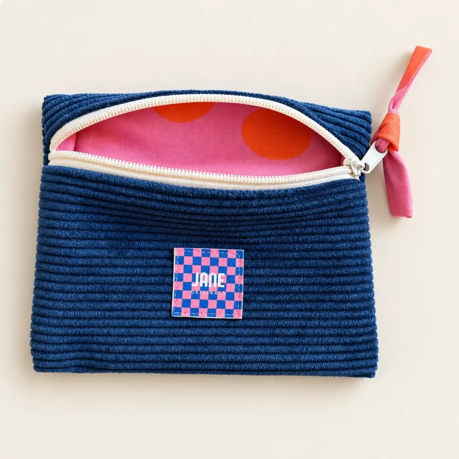 Pochette bleu marine ouverte sur sa doublure rose à grands pois orange