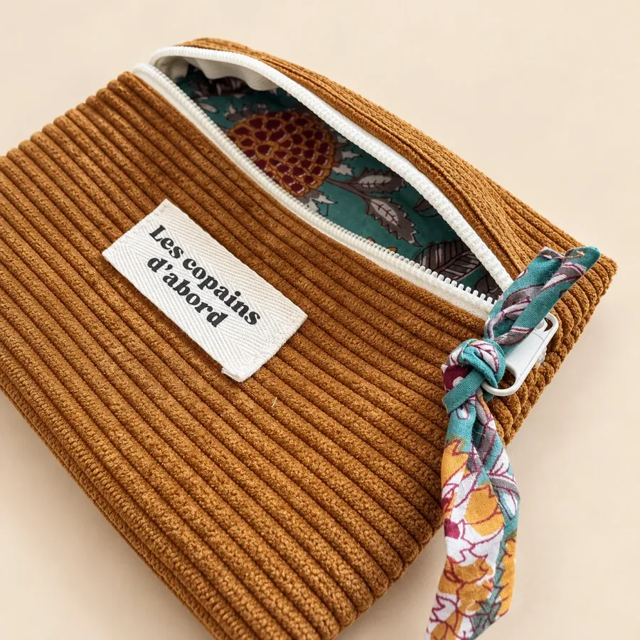 Pochette ocre vue de biais, doublure à grandes fleurs sur fond turquoise et tirette nouée assortie