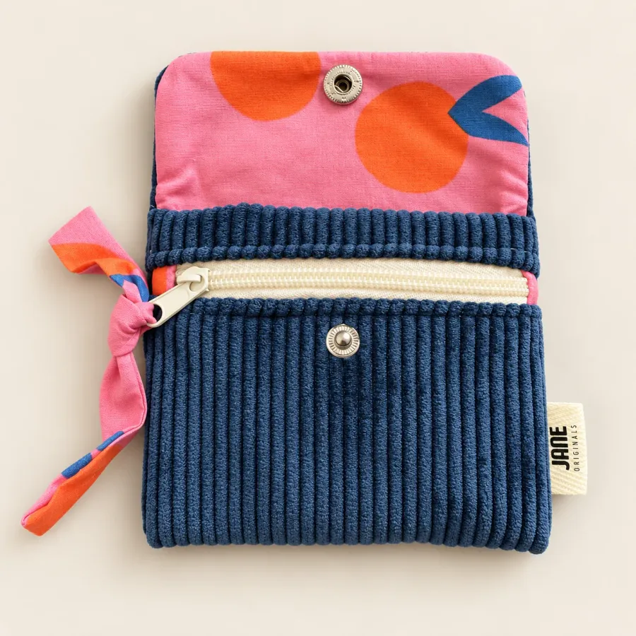 Porte-cartes bleu roi ouvert vu de dessus, rabat doublé d’un tissu rose à grands ronds orange, poche zippée écrue