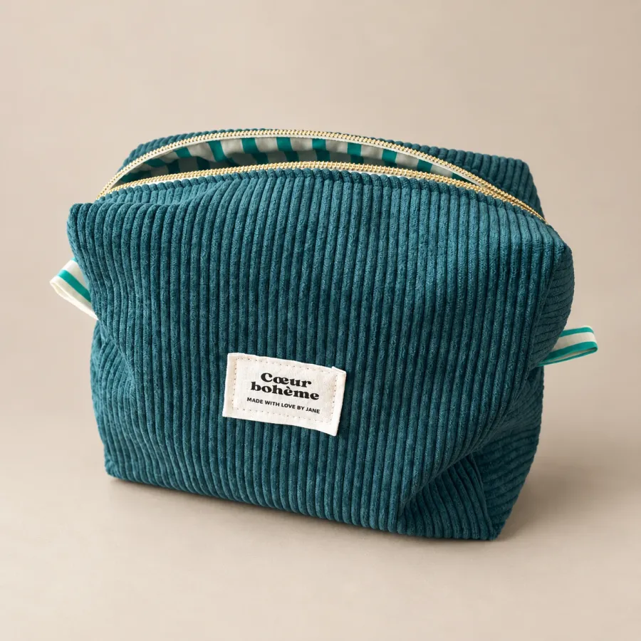 Trousse en velours bleu canard, fermeture dorée entrouverte sur sa doublure rayée, étiquette Cœur bohème